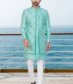 Turquoise sherwani with floral embroidery and white trousers—perfect for weddings.