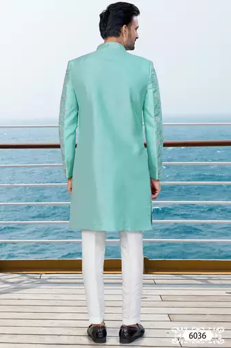 Turquoise sherwani with floral embroidery and white trousers—perfect for weddings.