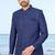 Navy blue sherwani with subtle texture, pocket square, and white trousers—ideal for weddings and formal events.