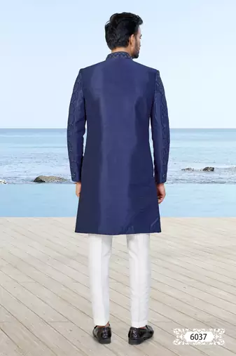 Navy blue sherwani with subtle texture, pocket square, and white trousers—ideal for weddings and formal events.