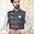 Maroon kurta and trousers paired with blue waistcoat featuring an intricate red pattern, gold-tone buttons