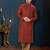 Rust-red kurta with a subtle all-over pattern and ornate gold-toned trim along the collar, placket and cuffs