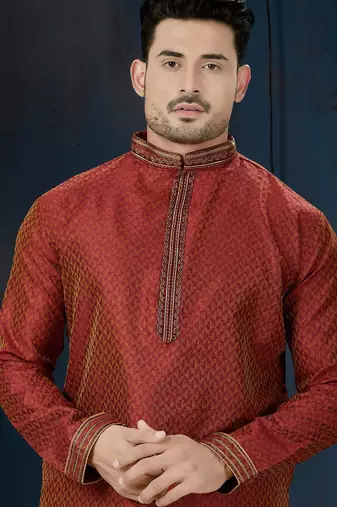 Rust-red kurta with a subtle all-over pattern and ornate gold-toned trim along the collar, placket and cuffs