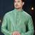 Sea-green kurta with an elegant tonal jacquard pattern, stand collar and gold-buttons, paired with gold trousers.
