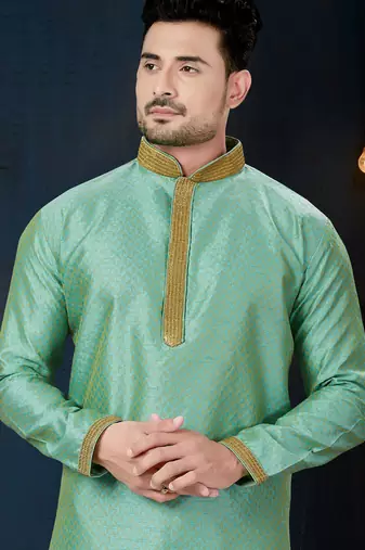 Mint-green kurta with a subtle woven pattern and gold-trimmed collar, placket and cuffs, paired with gold trousers.