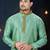 Mint-green kurta with a subtle woven pattern and gold-trimmed collar, placket and cuffs, paired with gold trousers.