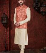 Coral-red and gold patterned nehru jacket paired with an ivory kurta and trousers—an elegant festive ensemble.