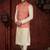 Coral-red and gold patterned nehru jacket paired with an ivory kurta and trousers—an elegant festive ensemble.