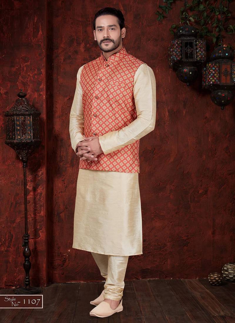 Coral-red and gold patterned nehru jacket paired with an ivory kurta and trousers—an elegant festive ensemble.
