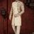 Fawn sherwani with floral sleeves, gold buttons, and matching trousers—ideal for weddings.