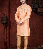 Peach sherwani with gold trim, ornate buttons, and matching pocket square.