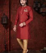 Maroon sherwani with gold trim, ornate buttons, and embroidered pocket square.