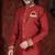Maroon sherwani with gold trim, ornate buttons, and embroidered pocket square.