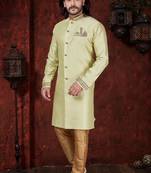 Light pistachio sherwani with gold-trimmed cuffs and collar, ornate buttons,& pocket square.