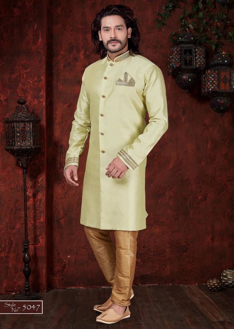 Light pistachio sherwani with gold-trimmed cuffs and collar, ornate buttons,& pocket square.