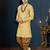 Mustard floral sherwani with pearl accessories, embellished pocket, and gold trousers.