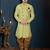 Light-yellow patterned sherwani with ornate buttons, burgundy pocket, and gold trousers.