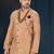 Peach patterned sherwani with pearl accessories, burgundy pocket, and gold trousers.