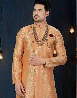 Peach jacquard sherwani with pearl accessories, burgundy pocket, and gold trousers. 2