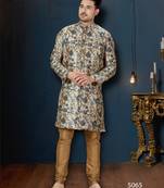 Cream floral sherwani with blue motifs, gold buttons, and gold trousers.