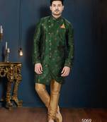 Emerald-green sherwani with floral motifs, gold pocket square, and gold trousers.
