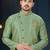 Mint-green patterned sherwani with asymmetrical front, gold pocket square, and gold trousers.