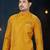 Mustard-yellow sherwani with jacquard texture, asymmetrical front, and matching pocket square.