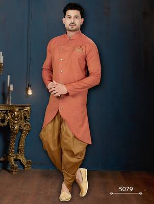 Coral-peach sherwani with textured finish, asymmetrical hem, pocket square, and gold trousers. 1