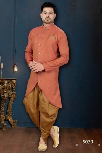 Coral-peach sherwani with textured finish, asymmetrical hem, pocket square, and gold trousers.