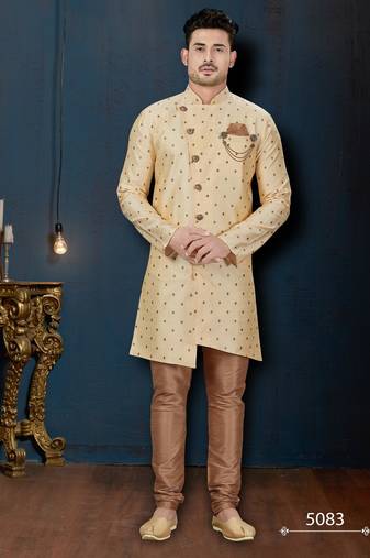 Cream sherwani with brown motifs, ornate buttons, chain pocket detail, and brown trousers.