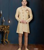 Cream sherwani with brown motifs, ornate buttons, chain pocket detail, and brown trousers.