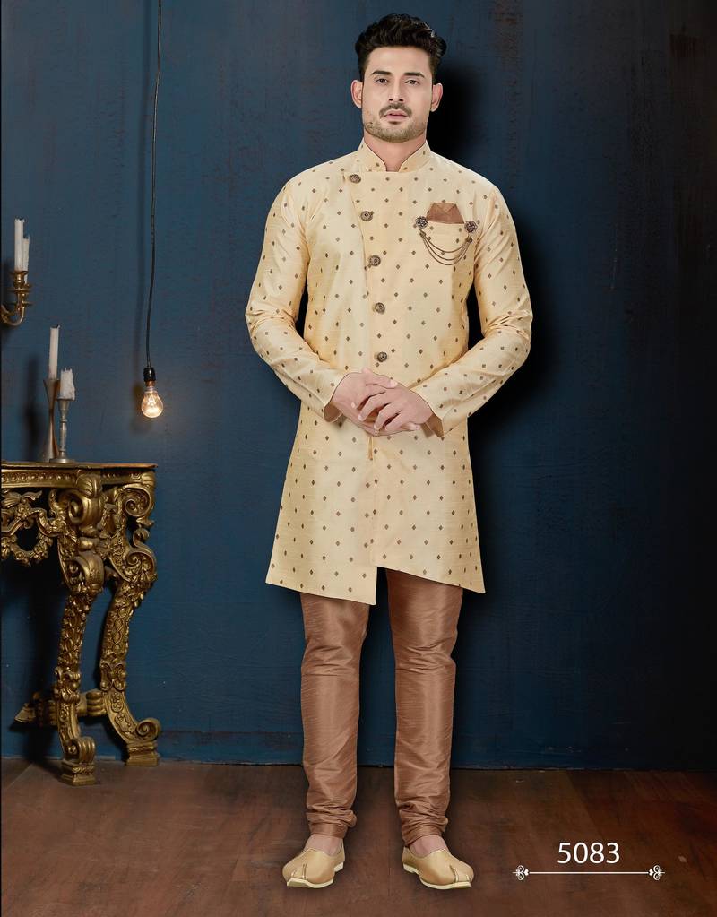 Cream sherwani with brown motifs, ornate buttons, chain pocket detail, and brown trousers.
