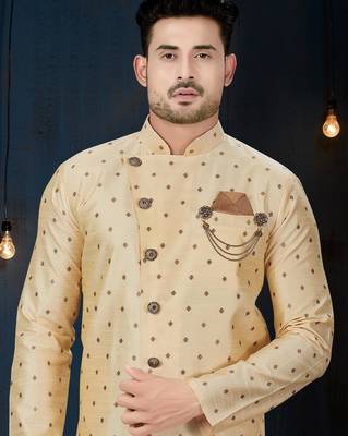 Cream sherwani with brown motifs, ornate buttons, chain pocket detail, and brown trousers. 2