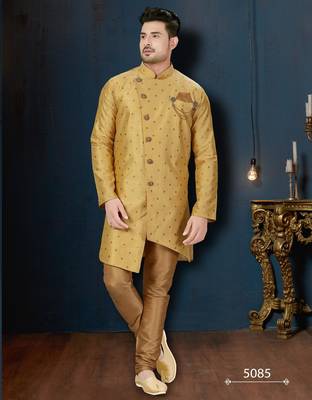 Mustard-gold sherwani with subtle motifs, ornate buttons, chain pocket detail, and gold trousers. 1