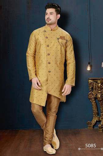 Mustard-gold sherwani with subtle motifs, ornate buttons, chain pocket detail, and gold trousers.