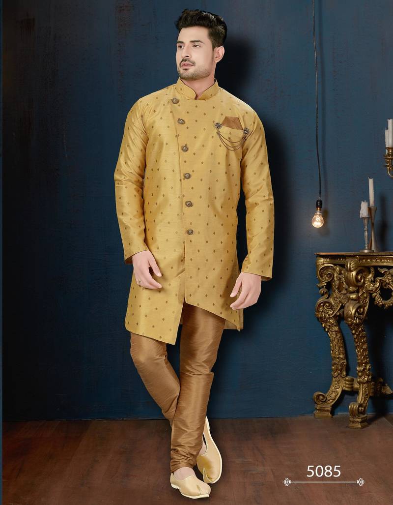 Mustard-gold sherwani with subtle motifs, ornate buttons, chain pocket detail, and gold trousers.