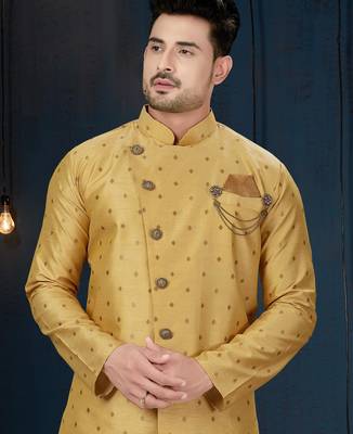 Mustard-gold sherwani with subtle motifs, ornate buttons, chain pocket detail, and gold trousers. 2