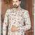 Off white floral sherwani with coral pocket accent and red trousers.