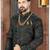 Dark blue sherwani with teal-rust botanical patterns, pearl accessories, and gold dhoti-style trousers.