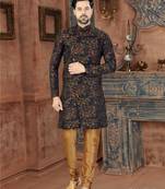 Dark blue sherwani with gold-rust botanical patterns and gold trousers.
