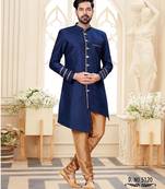 Beige sherwani with striped cuffs, chain pocket detail, and brown trousers.