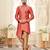 Coral-peach sherwani with gold piping, chain pocket, and gold trousers.