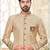 Beige sherwani with striped cuffs, chain pocket, and brown trousers.