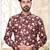Maroon floral sherwani with asymmetrical front, white pocket square, and white trousers.