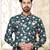 Deep-teal floral sherwani with asymmetrical front, ivory pocket square, and white trousers.