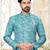 Teal-and-white patterned sherwani with asymmetrical front, matching pocket square, and white trousers.