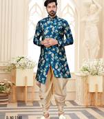 Teal floral sherwani with matching pocket square and cream dhoti-style trousers.