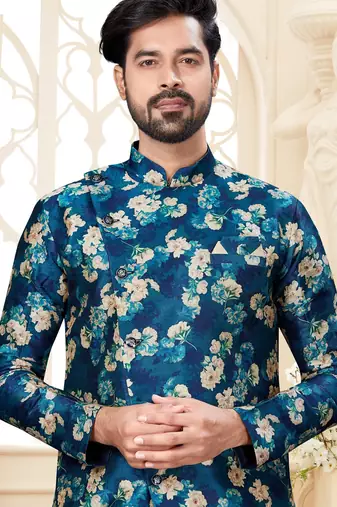 Teal floral sherwani with matching pocket square and cream dhoti-style trousers.